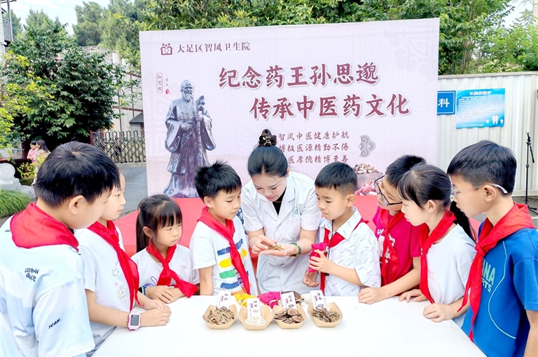 医务人员向小学生介绍香包所用中药材。