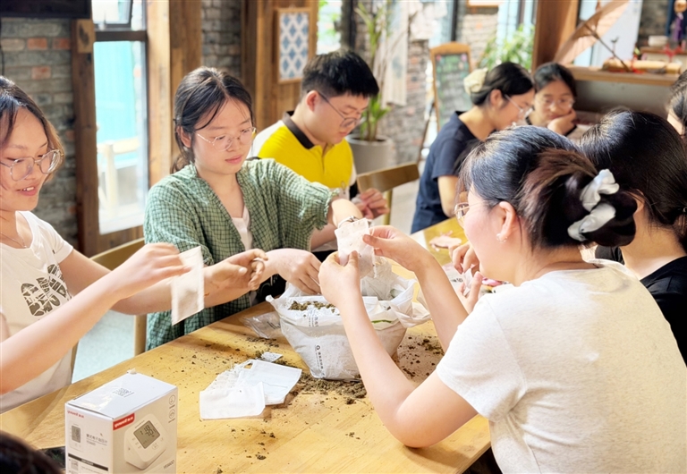 图为团队成员和旅客一起制作香包,香包所用的薄荷、艾草、藿香等原料均适配本地种植,既实用又成为自带传播属性的文旅小伴手礼。周承瑜摄