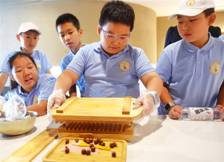 图为小学生在体验制作中药蜜丸。傅新春摄