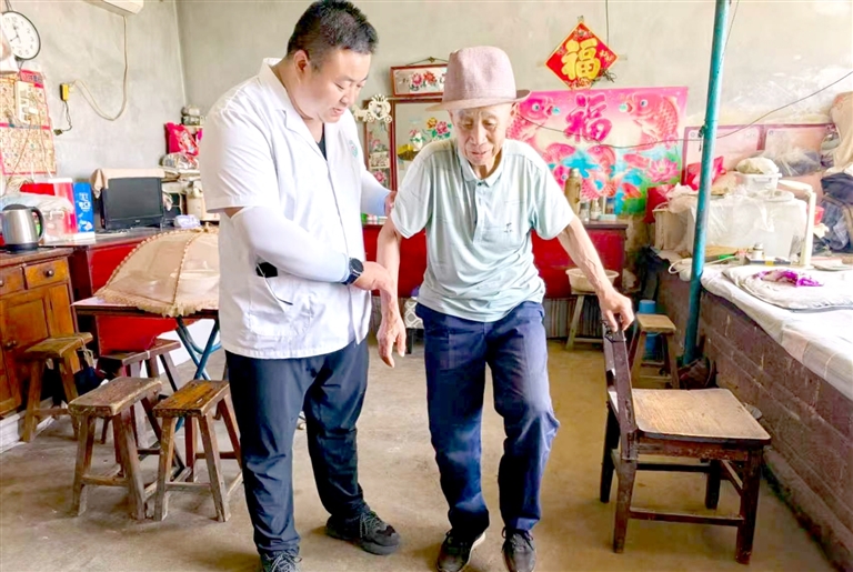 图为医务人员上门提供肢体功能训练。